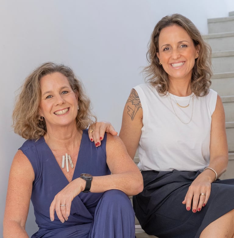 Two smiling women posing together for a portrait photo against a white background